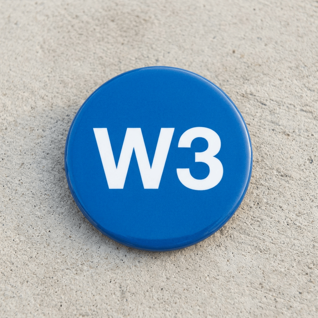 Blue circular button with white letters W3 on concrete surface